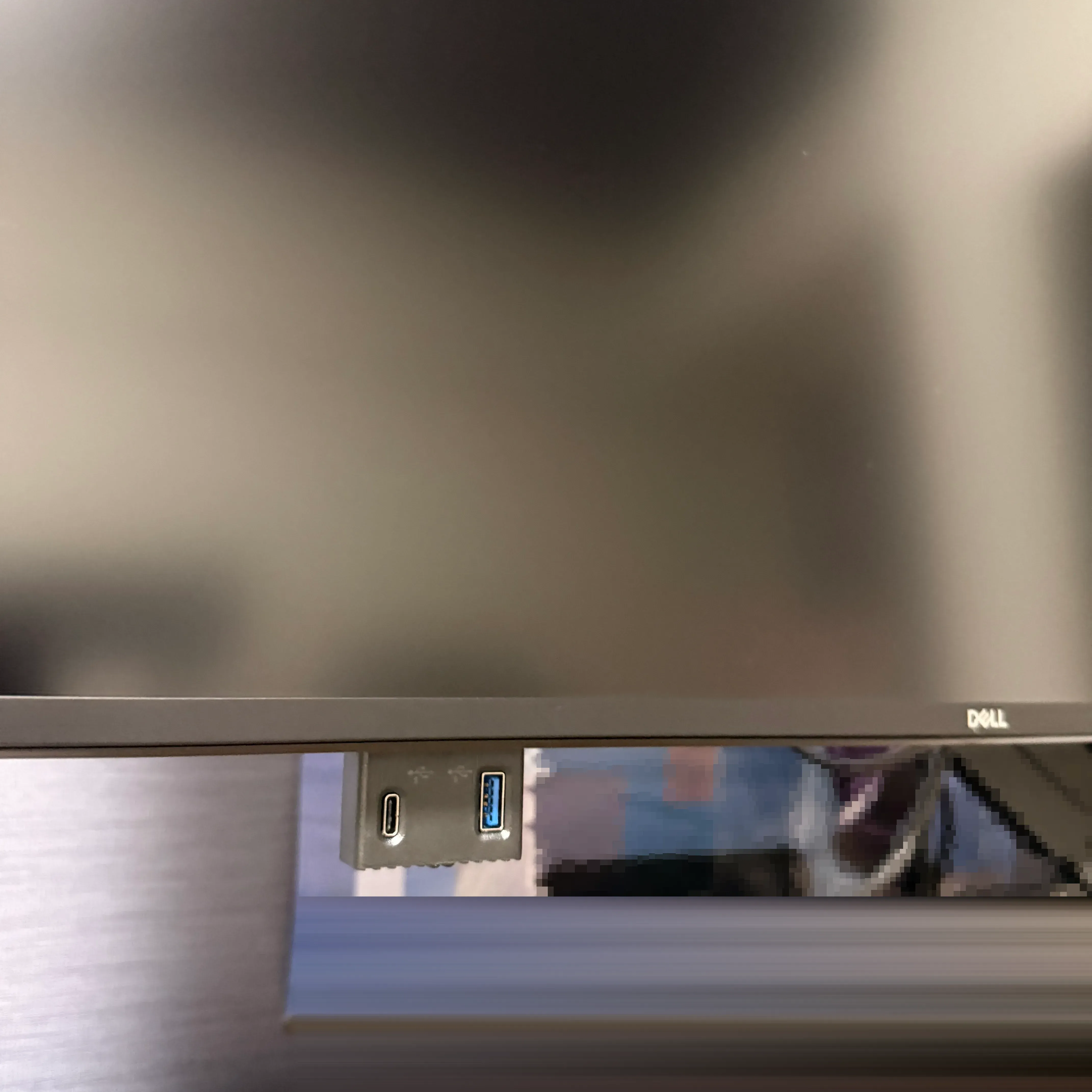 The USB-C and USB-A ports hidden on the underside of the monitor. They pop out when you push them in